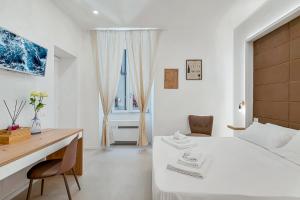 a white bedroom with a desk and a white bed at Grenni Guesthouse in La Spezia