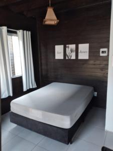 a large bed in a room with two windows at Pousada Tio Pietro in Imbituba