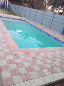 una piscina con pavimento piastrellato e una piscina di Cheapest Guest House in Klerksdorp a Klerksdorp