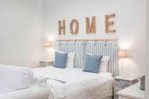 a white bedroom with a bed and a sign that reads home at Quinta das Essências in Penafiel