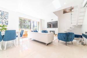 uma sala de estar com um sofá branco e cadeiras azuis em Apartment Aroeira Green Jodi em Aroeira