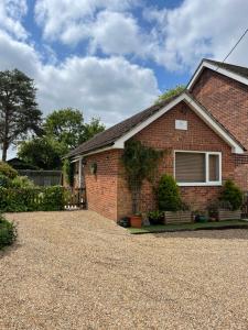 a brick house with a gravel driveway at Chestnut Cottage in East Bergholt