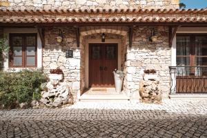 a stone house with a wooden door on a street at CASA DA PIA - Pia do Urso in Casais de São Mamede