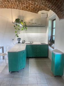 une cuisine avec des placards verts et un mur en briques dans l'établissement La Dimora delle Viole, à Lauriano