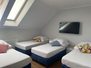 Habitación con 3 camas y TV de pantalla plana. en Noclegi Budomas Klima-ParkigFree-SmartTv, en Wroclaw
