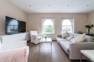 uma sala de estar com um sofá e uma televisão em Spacious Modern One Bedroom Flat in Chelsea em Londres