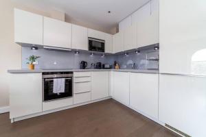 uma cozinha branca com armários e electrodomésticos brancos em Spacious Modern One Bedroom Flat in Chelsea em Londres