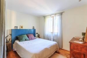 1 dormitorio con 1 cama con cabecero azul y ventana en Maison grande terrasse aux portes des Calanques, en Marsella