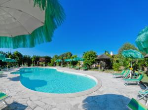 - une piscine dans un complexe avec des chaises et des parasols dans l'établissement Masseria Pisciani, à Torchiarolo