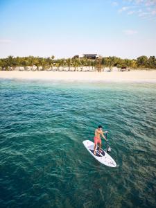 a man riding a paddle board in the ocean at Chablé Maroma in Playa del Carmen