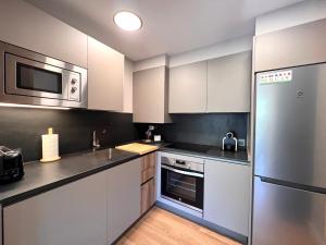 a kitchen with white cabinets and a stainless steel refrigerator at Dúplex La Solana in Sort
