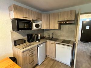 a small kitchen with wooden cabinets and a microwave at Studio cosy au pied des pistes avec balcon, proche centre et piscine, navette gratuite - FR-1-515-172 in Villard-de-Lans