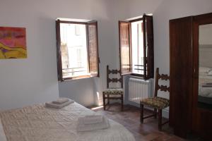 トーディにあるCasa Di Borgoのベッドルーム1室(ベッド1台、椅子2脚、窓2つ付)