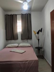 1 dormitorio con cama con sábanas rosas y ventana en Guarapari centro, en Guarapari