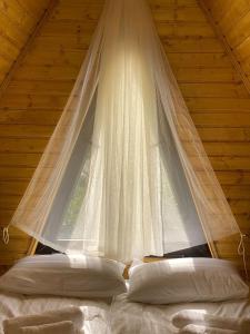 Un dormitorio con una cortina blanca colgando sobre una cama en Sunny Side Cottage, en Kazbegi
