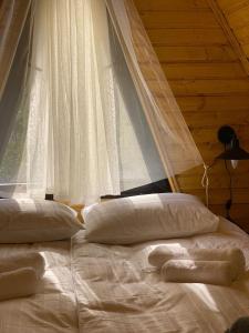 a bed with white sheets and pillows in front of a window at Sunny Side Cottage in Stepantsminda