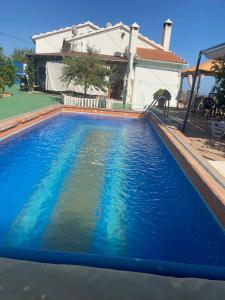 a swimming pool with blue water in front of a house at Casa Rural Zinho in Arenas