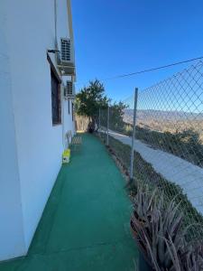 a building with a fence and a green sidewalk at Casa Rural Zinho in Arenas