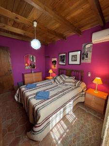 a bedroom with a large bed with purple walls at Casa Rural Zinho in Arenas