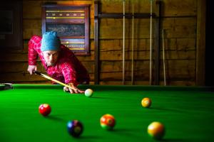 a man playing billiard with a cue on a pool table at Emerald Lake Lodge in Field
