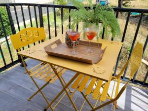 a wooden table with two glasses on a balcony at cosy, spacieux, avec balcon, au calme in Artigues-près-Bordeaux