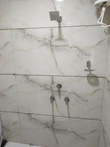 a white marble shower with two faucets in a bathroom at Hotel shipra suites in Ujjain