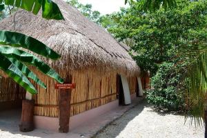 a hut with a straw roof with a sign in front at Kakao Cobá Hotel & Cenote Experience in Cobá