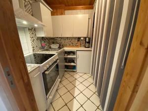 una pequeña cocina con armarios blancos y suelo de baldosa. en La Casa Nostra in Asker, only 17 minutes to Oslo, en Asker