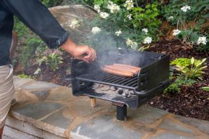 a person cooking a hot dog on a grill at 6 Pine Luxury Treehouse near Lake Guntersville in Scottsboro