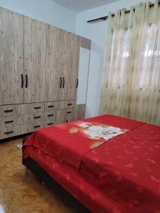 a bedroom with a red bed and wooden cabinets at Unik Private Villa Center in Velipojë