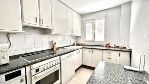 a white kitchen with white cabinets and a sink at Wallada Vistalegre in Córdoba