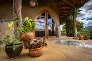 a porch with potted plants and a large window at Casa Samai Boutique in Samaipata