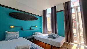 Zimmer mit 2 Betten und einem Surfbrett an der Wand in der Unterkunft Sardines and Friends Hostel 04 in Póvoa de Varzim