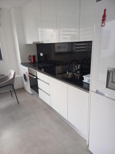 Una cocina con gabinetes blancos y una encimera negra. en La Calicia - Residência Marina, en Praia