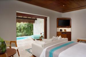 a bedroom with a bed and a tv and a pool at Chablé Maroma in Playa del Carmen