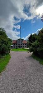 uma casa com um mastro de bandeira no meio de uma estrada em Sjötorps Säteris 1600-tals Huvudbyggnad em Larv