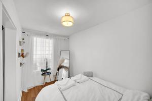 a white bedroom with a bed and a lamp at Logan Square Coach House in Chicago