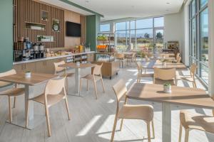 a restaurant with tables and chairs and windows at Element San Jose Milpitas in Milpitas