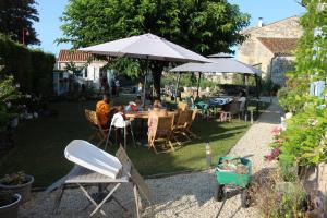 a group of people sitting at a table under an umbrella at La Charentaise des Lilas in Saint-Léger