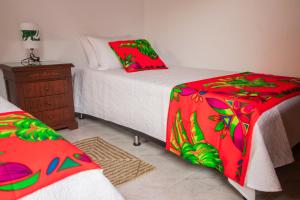 um quarto com 2 camas com lençóis vermelhos e verdes em Etnias Hotel tematico em Quibdó
