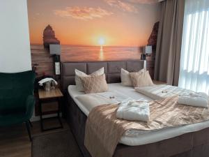 a bedroom with a bed with a sunset mural on the wall at Hotel Ammerländer Hof in Westerstede