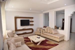 - un salon avec deux canapés et une télévision dans l'établissement Appartements neufs et modernes entre ter et mer, à Soliman