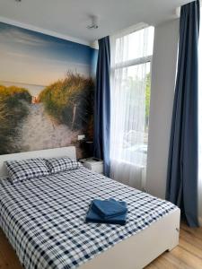 een slaapkamer met een bed met een geruite deken en een strandmuurschildering bij Pokoje przy Plaży Sopot in Sopot