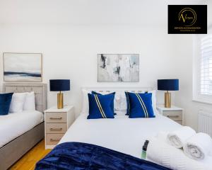 2 łóżka z białymi i niebieskimi poduszkami w sypialni w obiekcie Luxury Home by AV Stays Short Lets Sidcup w mieście Sidcup