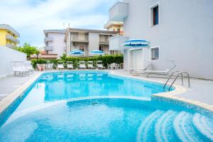 uma piscina com cadeiras e guarda-sóis ao lado de um prédio em Feel Good em Rimini