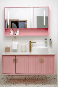 uma casa de banho rosa com um lavatório e um espelho em The Pink Palm Hotel - Adults Only em Charlotte Amalie