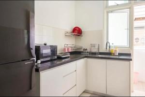uma cozinha com armários brancos e um micro-ondas em Spice Arena Guesthouse em Bayan Lepas