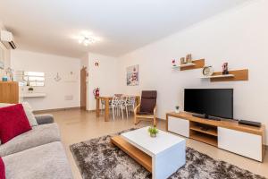uma sala de estar com um sofá e uma televisão em Rossio Sea View By ALzira em Albufeira
