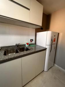 a kitchen with a sink and a white refrigerator at DEPTO EN AV ROCA PARA HASTA 4 PERSONAS - Edificio MIRÓ2 in Santiago del Estero