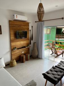 Una sala de estar con televisión y un sofá. en Trancoso43 - Lindo apartamento 1 suíte , sala com varanda, en Trancoso